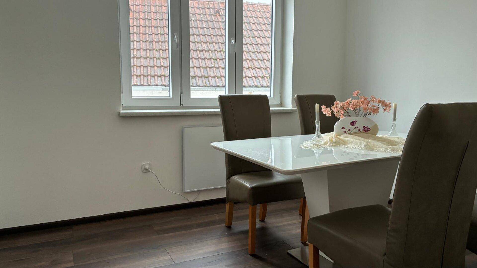 Heller Essbereich mit modernem weißen Tisch, bequemen Stühlen und dunklem Laminatboden.