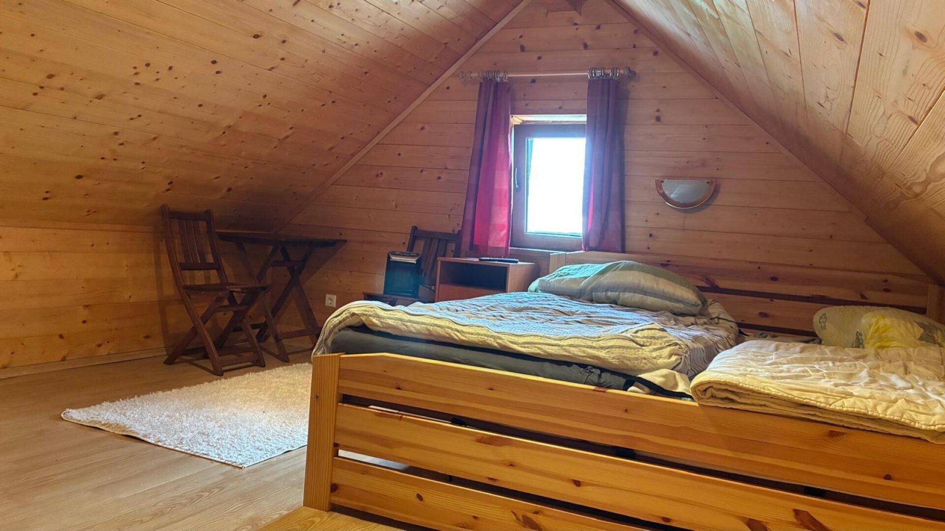 Gemütliches Schlafzimmer im Dachgeschoss mit Holztäfelung und schrägen Decken.