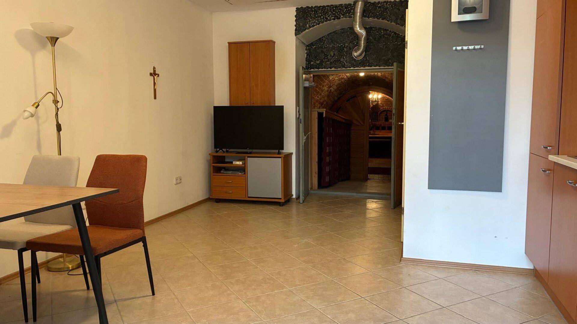 Wohnbereich mit Fernseher und Essgelegenheit, angrenzend an den rustikalen Weinkeller.