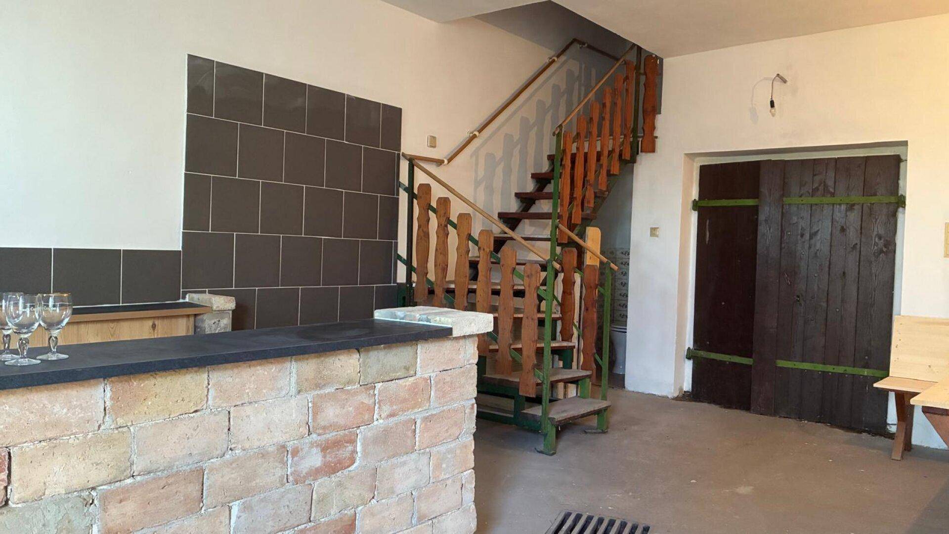 Eingangsbereich mit rustikaler Treppe, gemauertem Tresen und gefliestem Wandbereich.