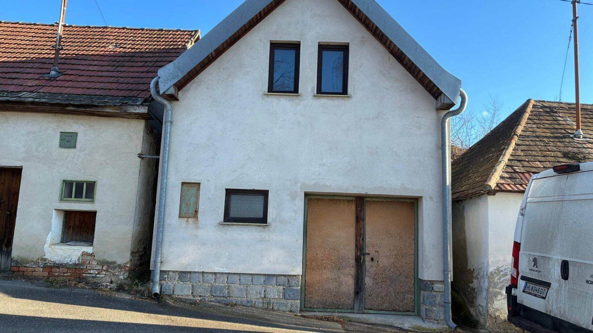 Traditionelles Gebäude mit verputzter Fassade, Satteldach und Holztüren.