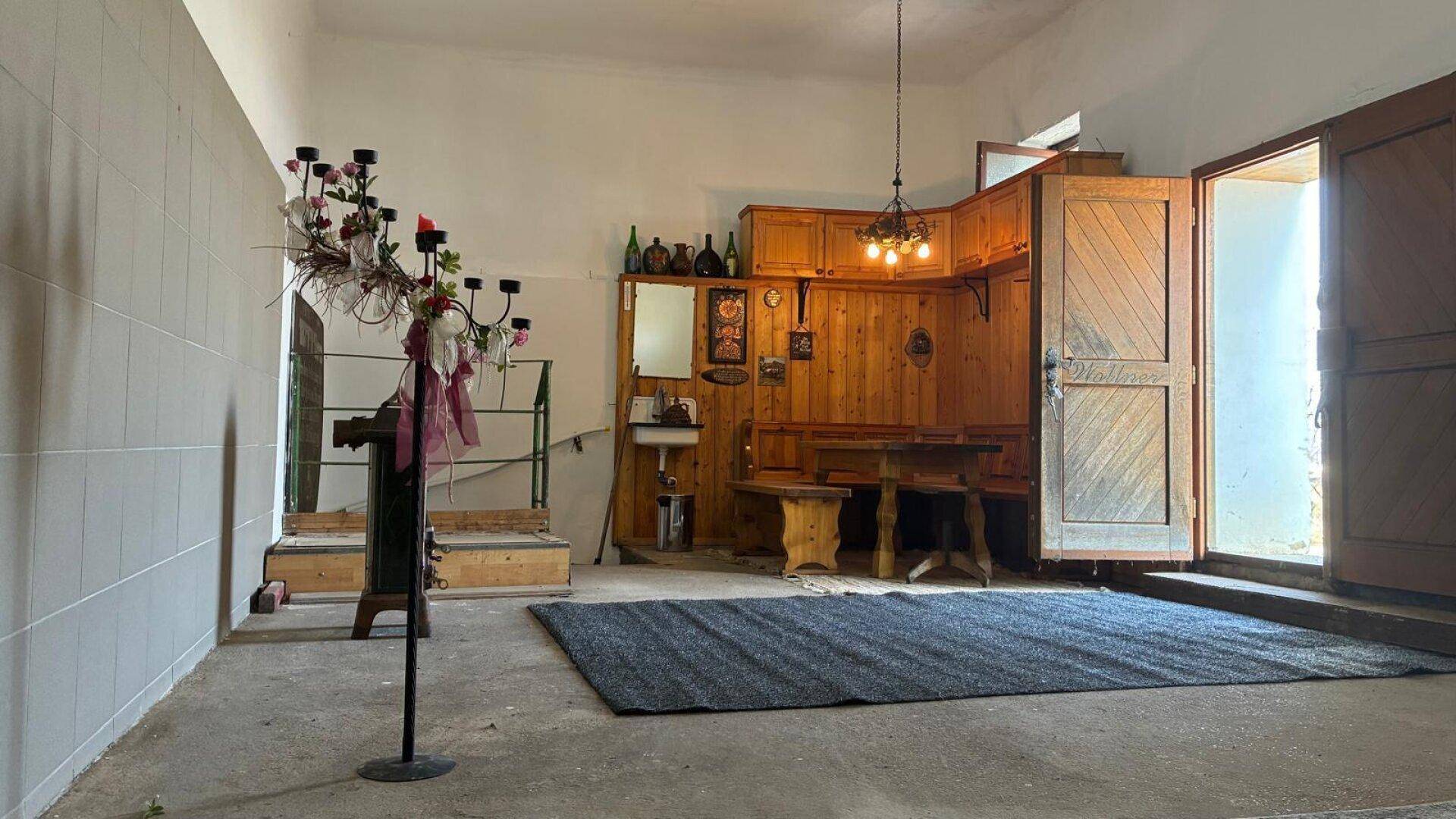 Heller Innenraum mit rustikalen Holzelementen, einem Ofen und einem Teppich auf dem Boden.