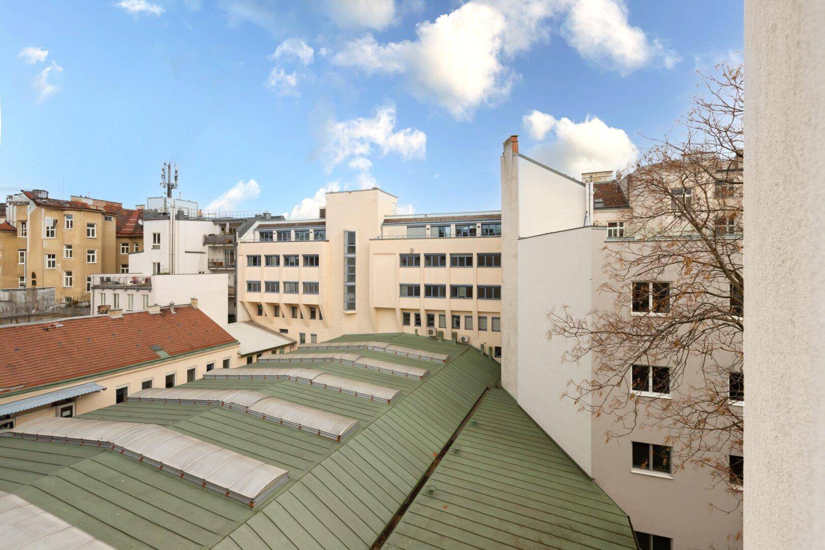 Blick über die Dächer der Stadt mit verschiedenen Gebäuden und einem weiten Himmel.
