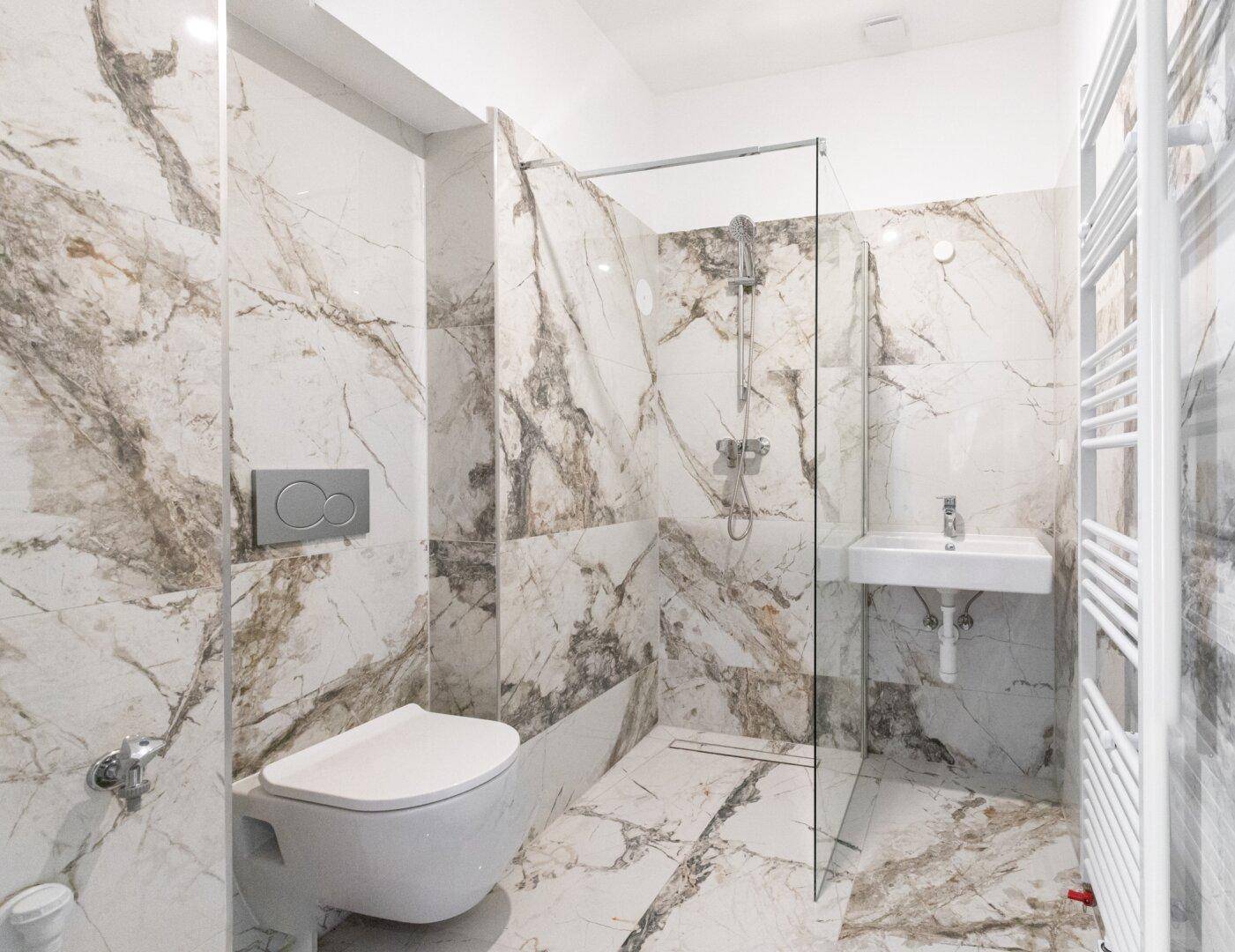 Modernes Badezimmer mit Marmorfliesen, ebenerdiger Dusche und wandhängendem WC.
