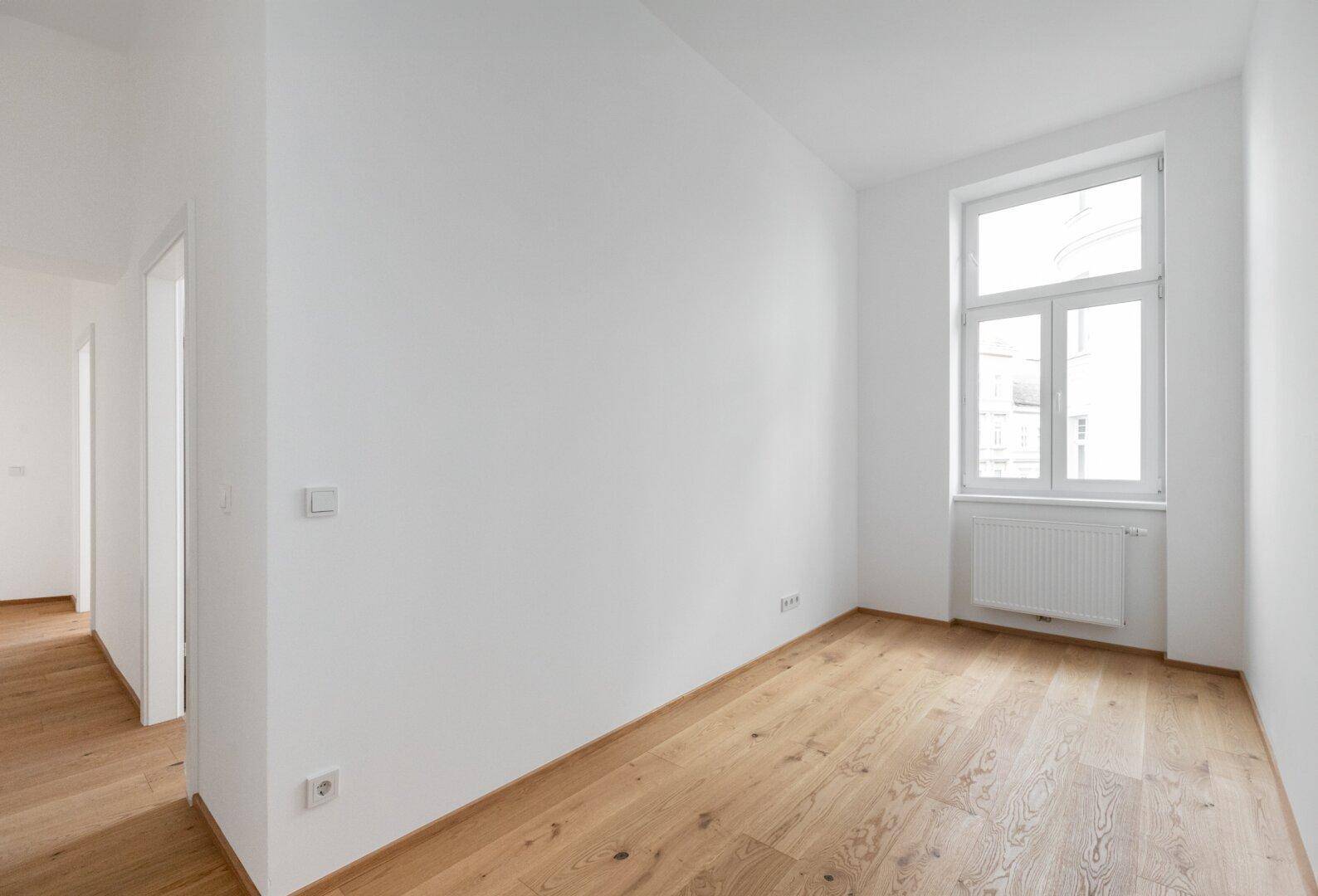 Kleineres, helles Zimmer mit Parkettboden und einem Fenster, geeignet als Kinder- oder Arbeitszimmer.