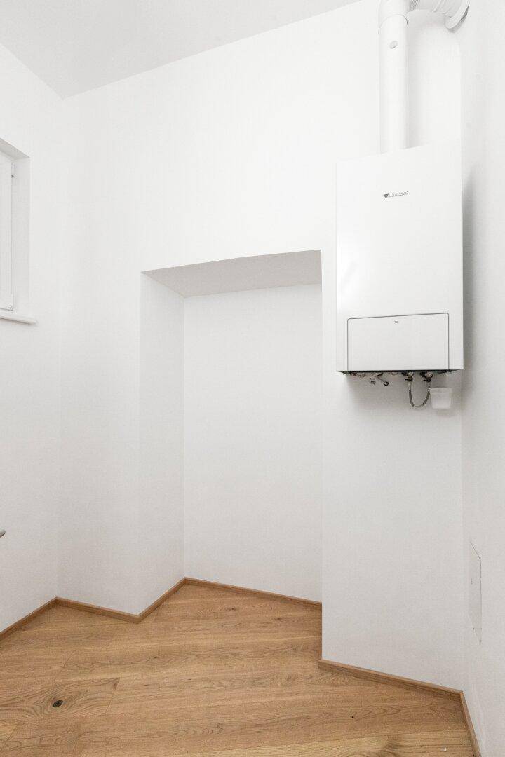 Hauswirtschaftsraum mit Gastherme, Fenster und Platz für Waschmaschine oder Abstellmöglichkeiten.