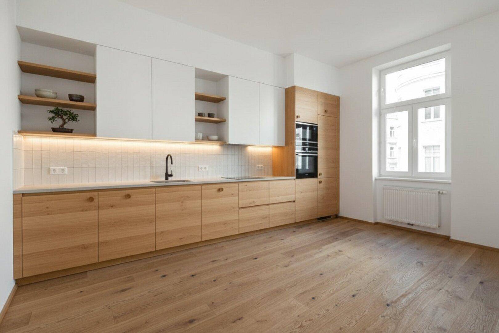 Moderne Küche mit hellen Holzfronten, weißen Oberschränken und integrierten Geräten.
