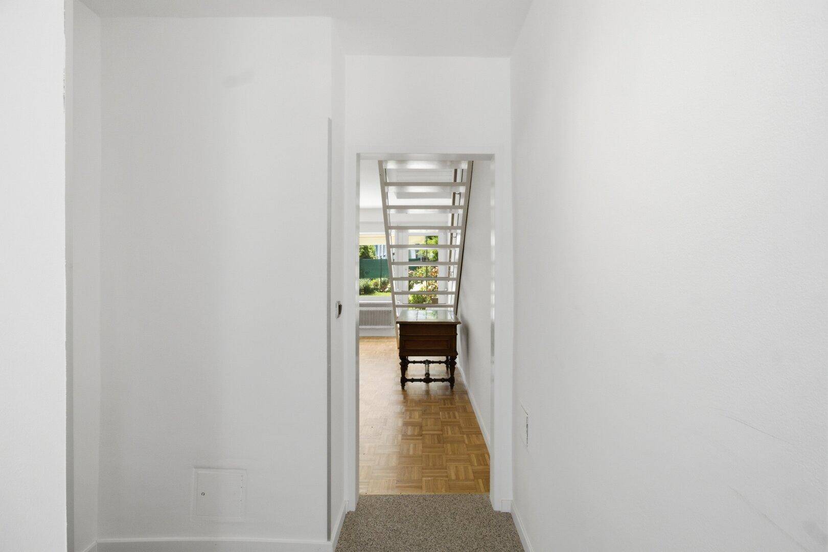 Heller Flur mit Teppichboden und Blick auf die offene Treppe im Wohnbereich.