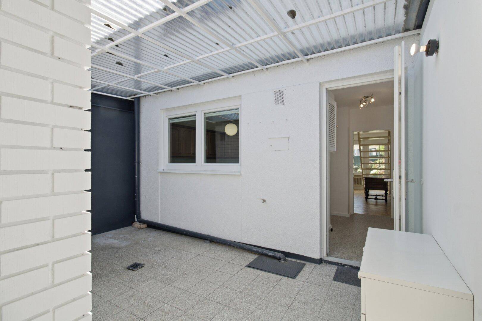 Heller, überdachter Außenbereich mit Fliesenboden und Zugang zum Haus, vielseitig nutzbar.