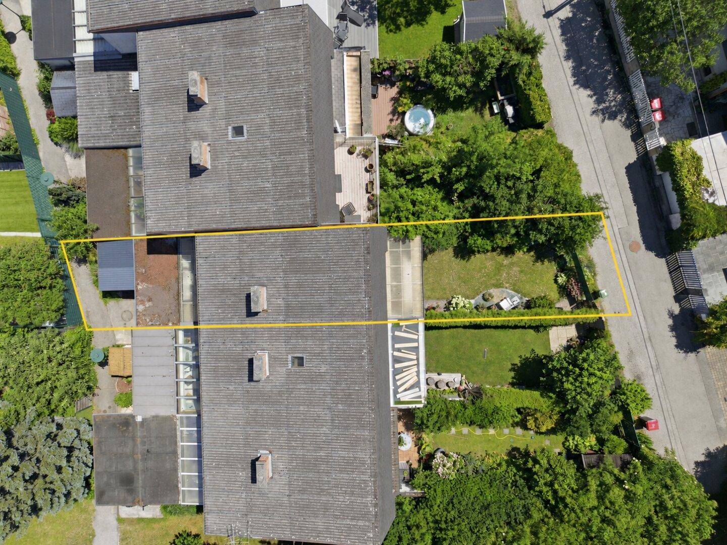 Vogelperspektive eines Reihenhauses mit Garten und Grundstücksgrenzen, umgeben von weiteren Häusern.