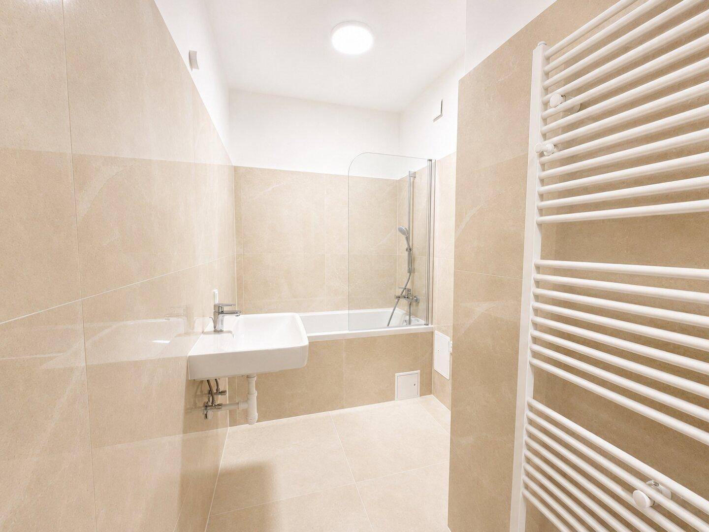 Helles Badezimmer mit Badewanne, Duschabtrennung und Fliesenboden.