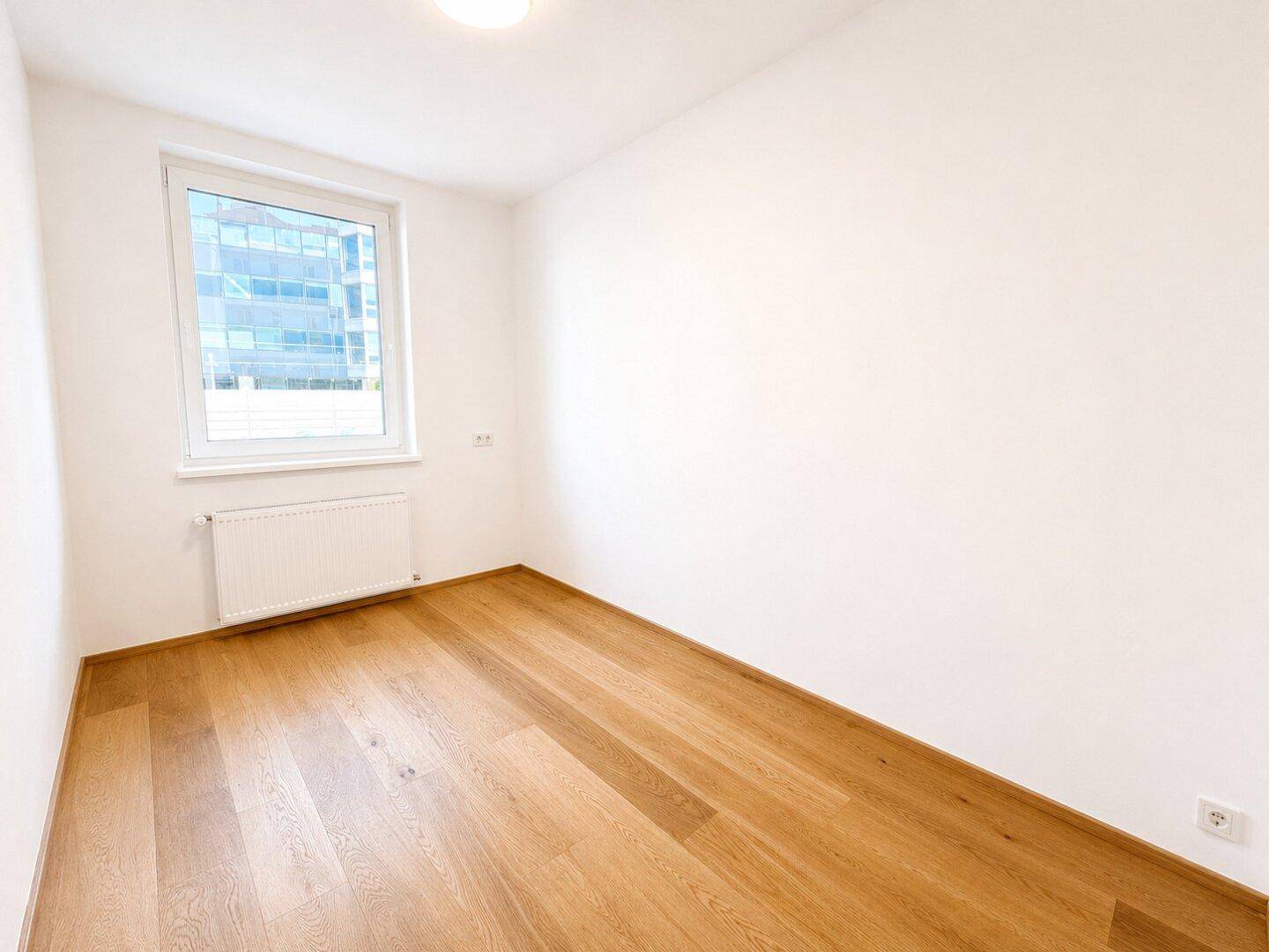Heller Raum mit Holzparkett und Fenster, ideal als Büro oder Gästezimmer.