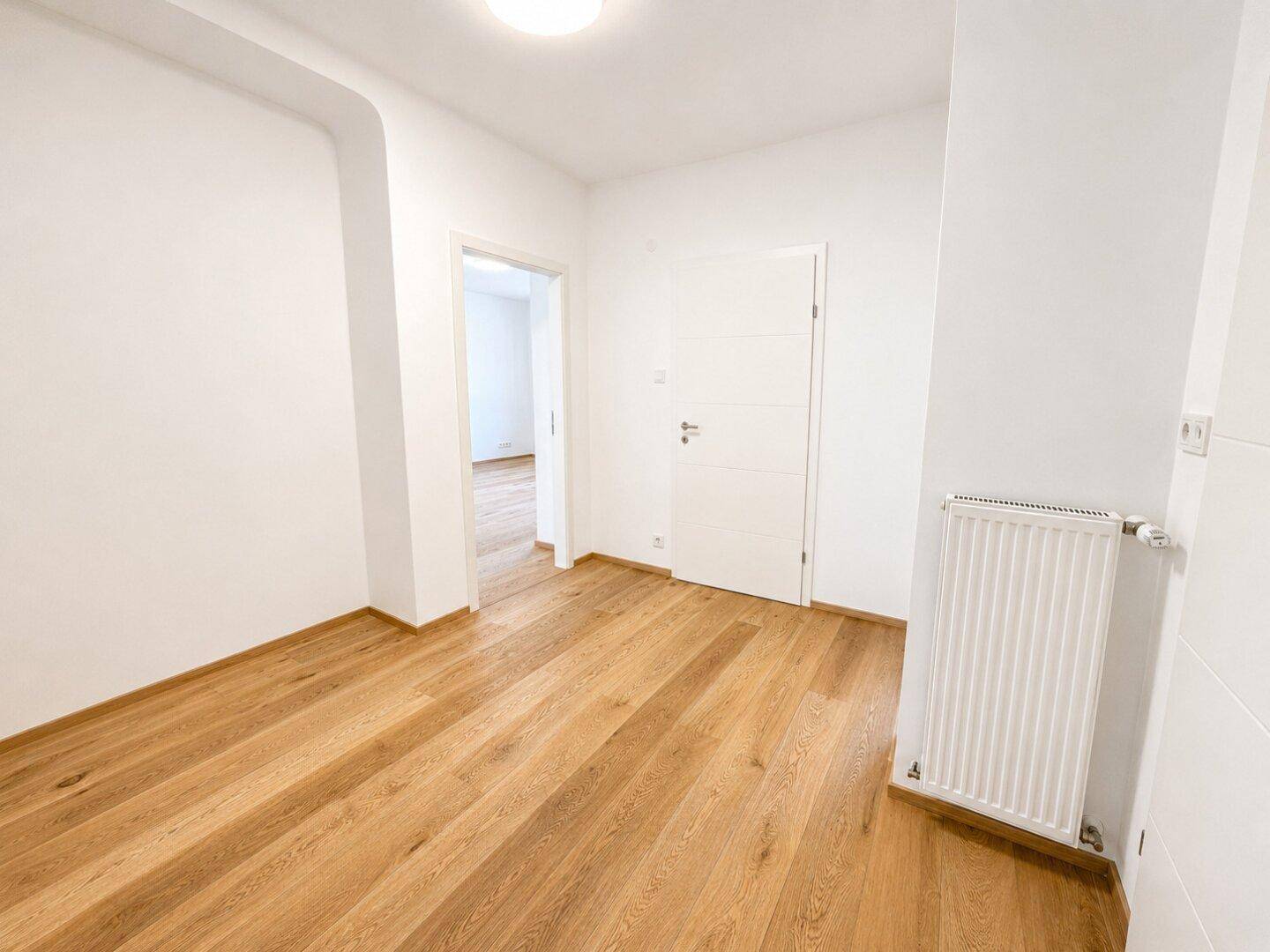 Heller Flur mit Holzfußboden und Zugang zu den Wohnräumen.
