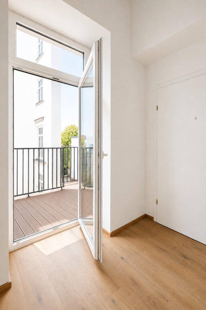 Heller Raum mit Zugang zu einem Balkon und Holzboden.