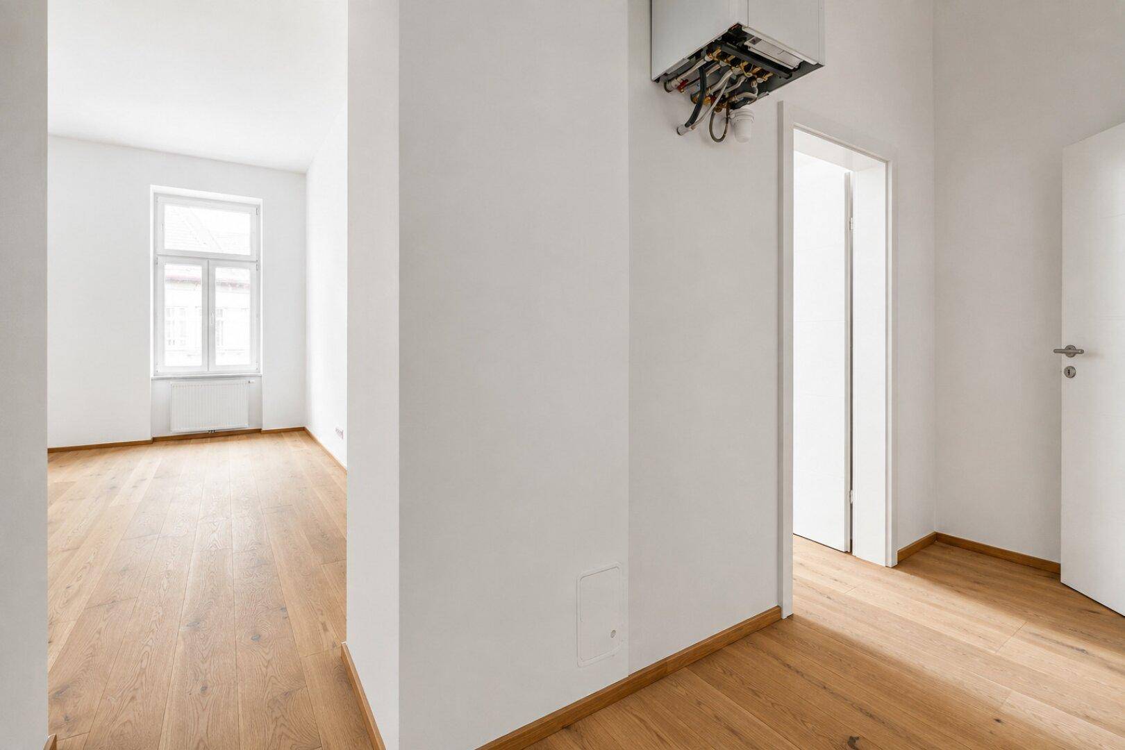 Heller Flur mit Holzboden und Zugang zu weiteren Räumen.