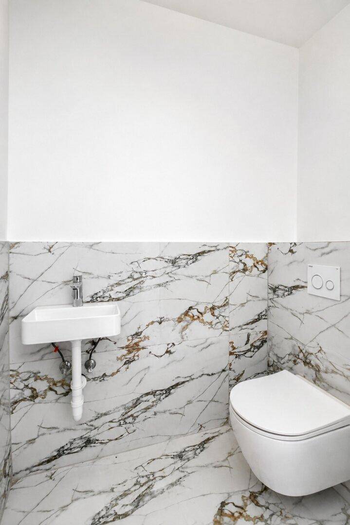 Helles Gäste-WC mit Marmorfliesen und wandhängendem WC.
