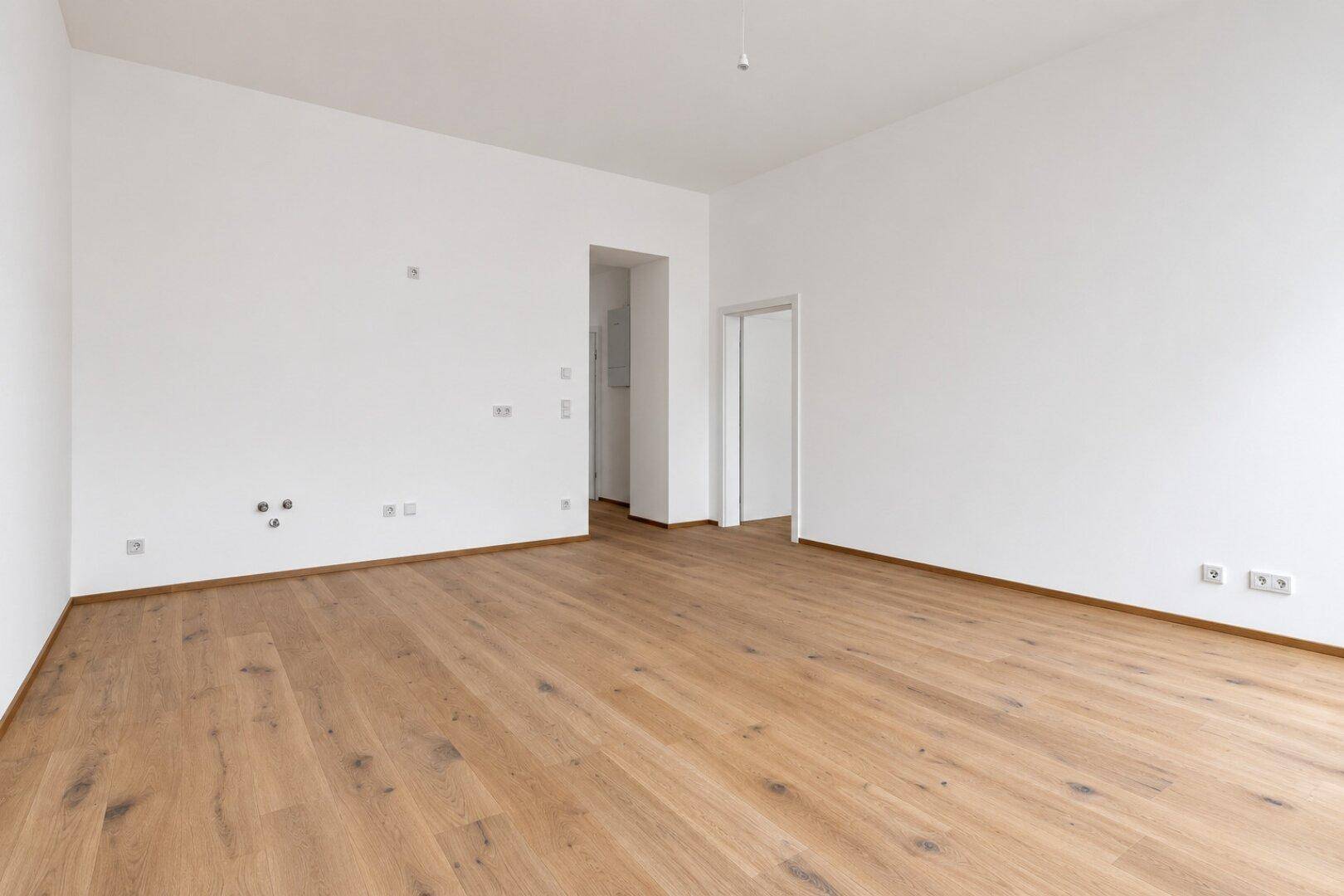 Heller, leerer Raum mit Holzboden und weißen Wänden, bereit zur individuellen Gestaltung.