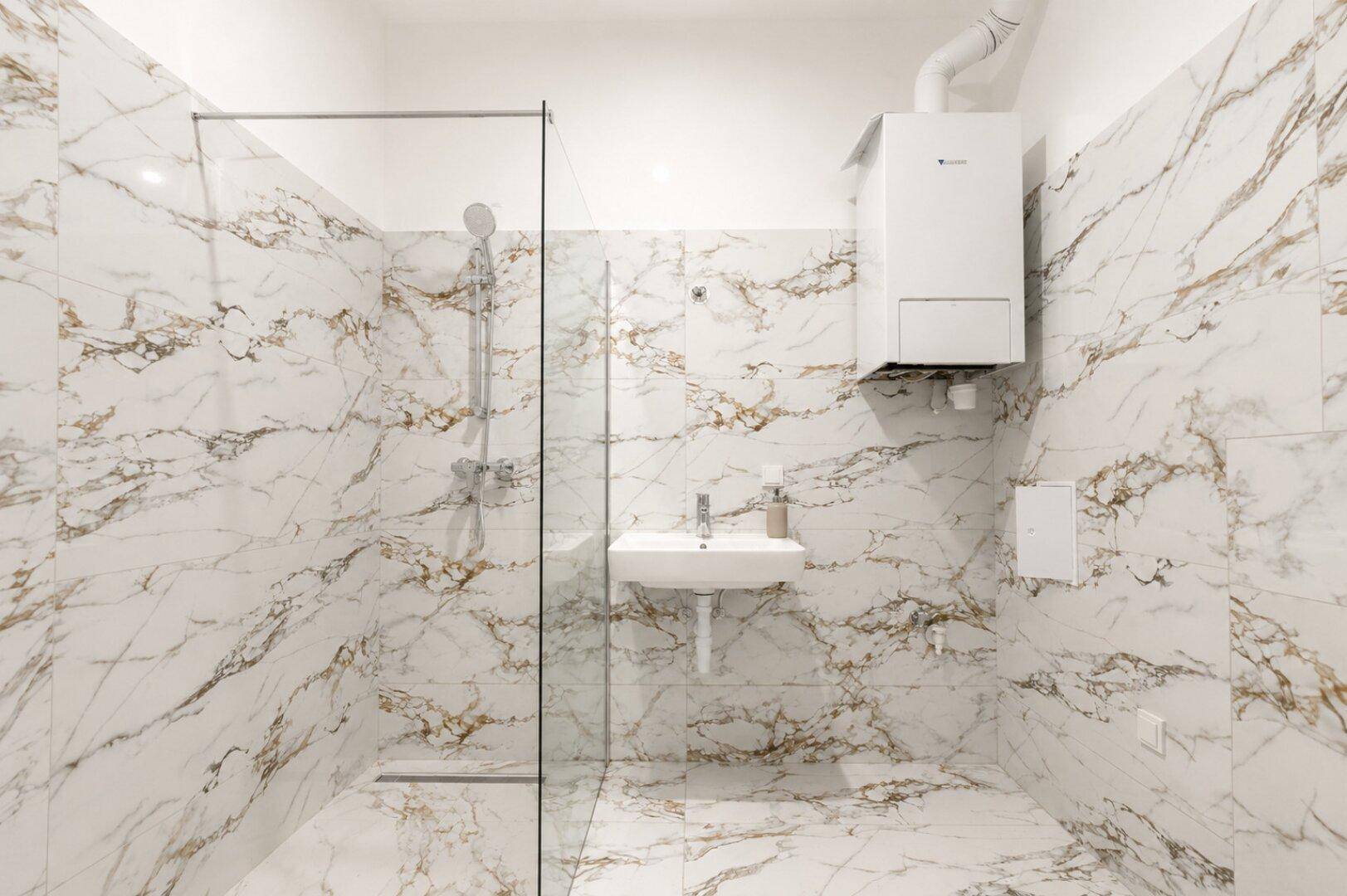 Modernes Badezimmer mit eleganten Marmorfliesen, ebenerdiger Dusche und wandhängendem Waschbecken.