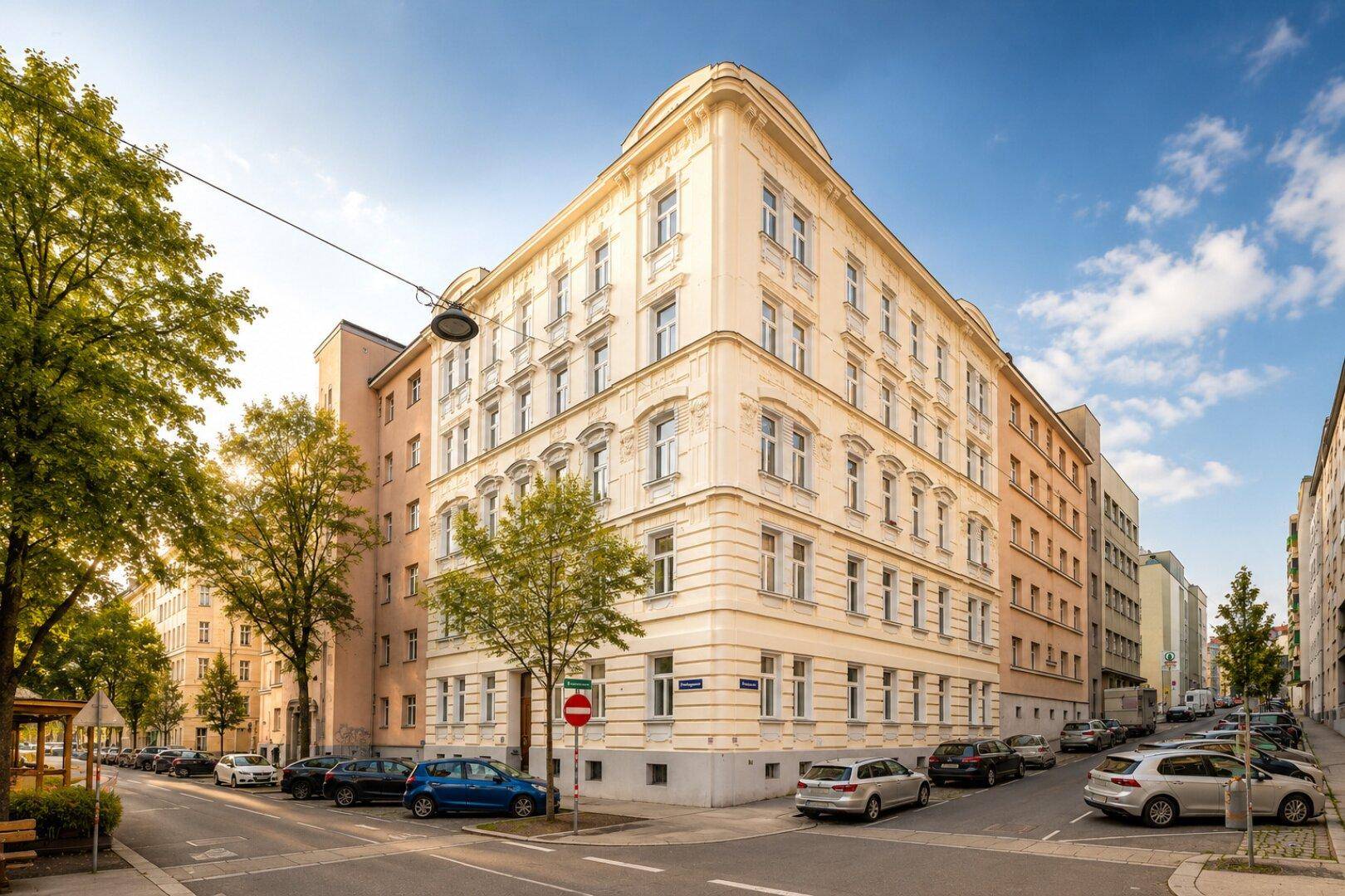 Historisches Eckgebäude mit klassischer Architektur und vielen Fenstern in einer städtischen Umgebung.