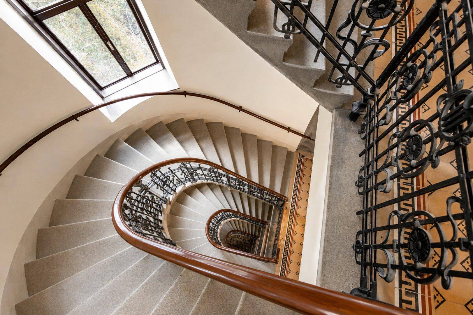 Beeindruckendes, spiralförmiges Treppenhaus mit schmiedeeisernem Geländer und Oberlicht, das viel Licht spendet.