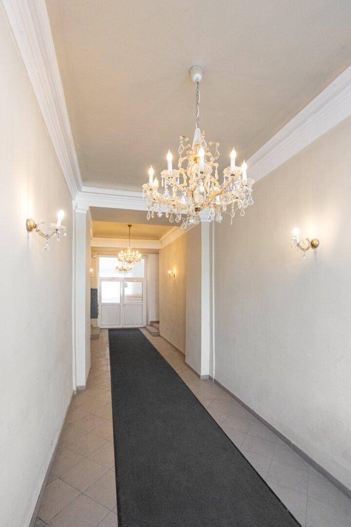 Langer Eingangsbereich mit Teppichläufer, eleganten Kronleuchtern und Wandleuchten.