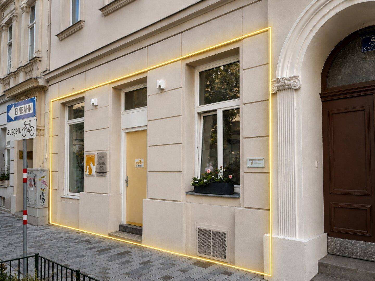 Detailansicht des Eingangs im Erdgeschoss mit klassischer Architektur und Fensterbank mit Blumen.
