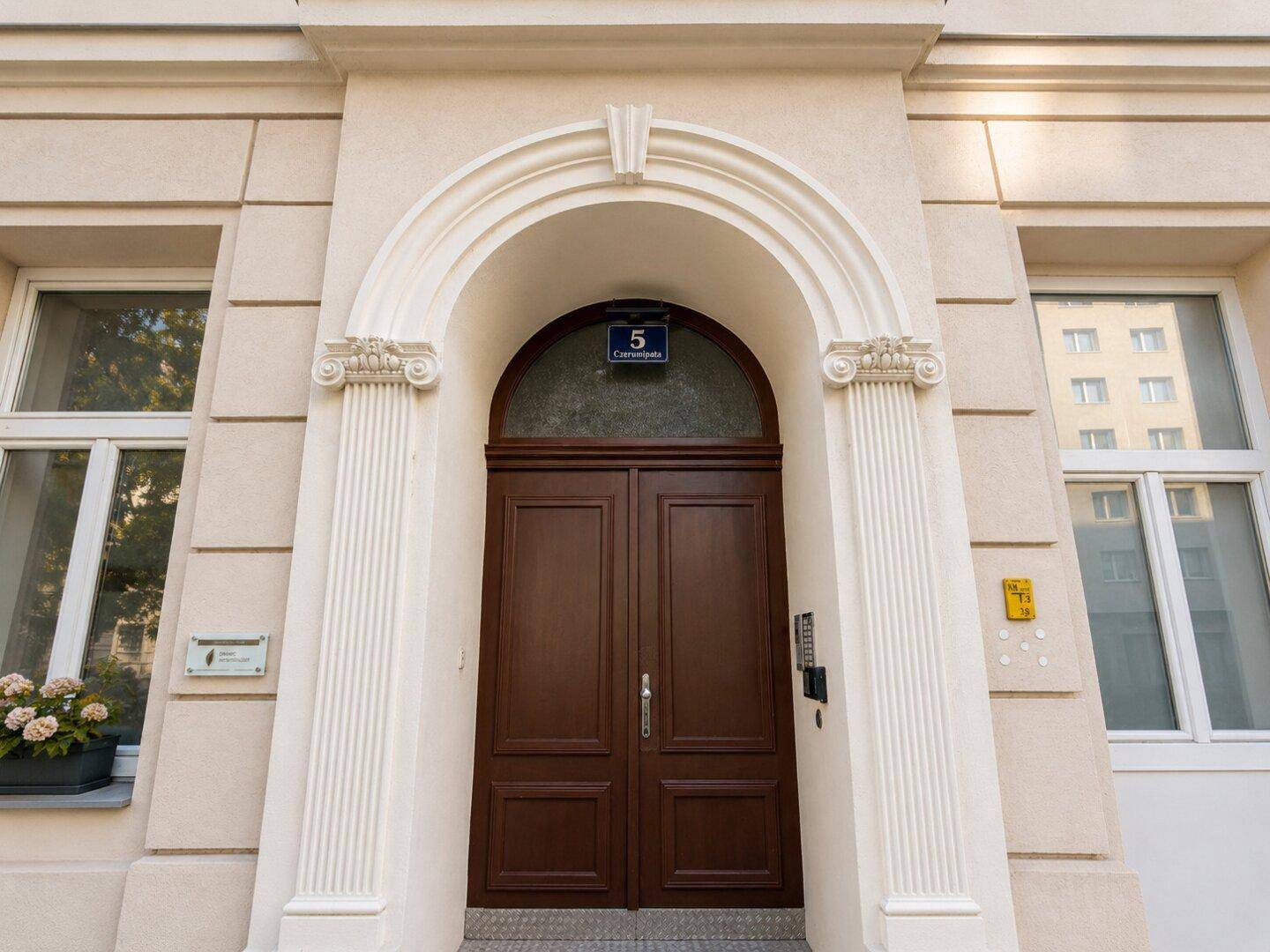 Detailansicht des Haupteingangs mit Holztür und klassischer Fassadenverzierung.