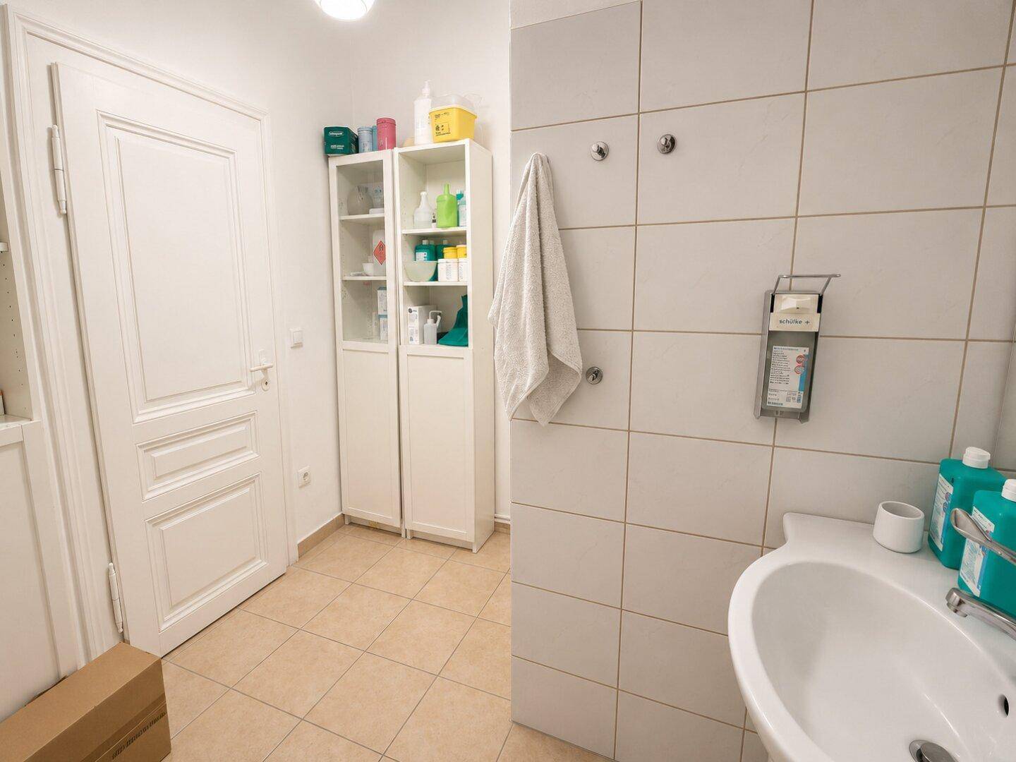 Kleiner Waschraum mit Fliesenwänden, Waschbecken und Stauraum.