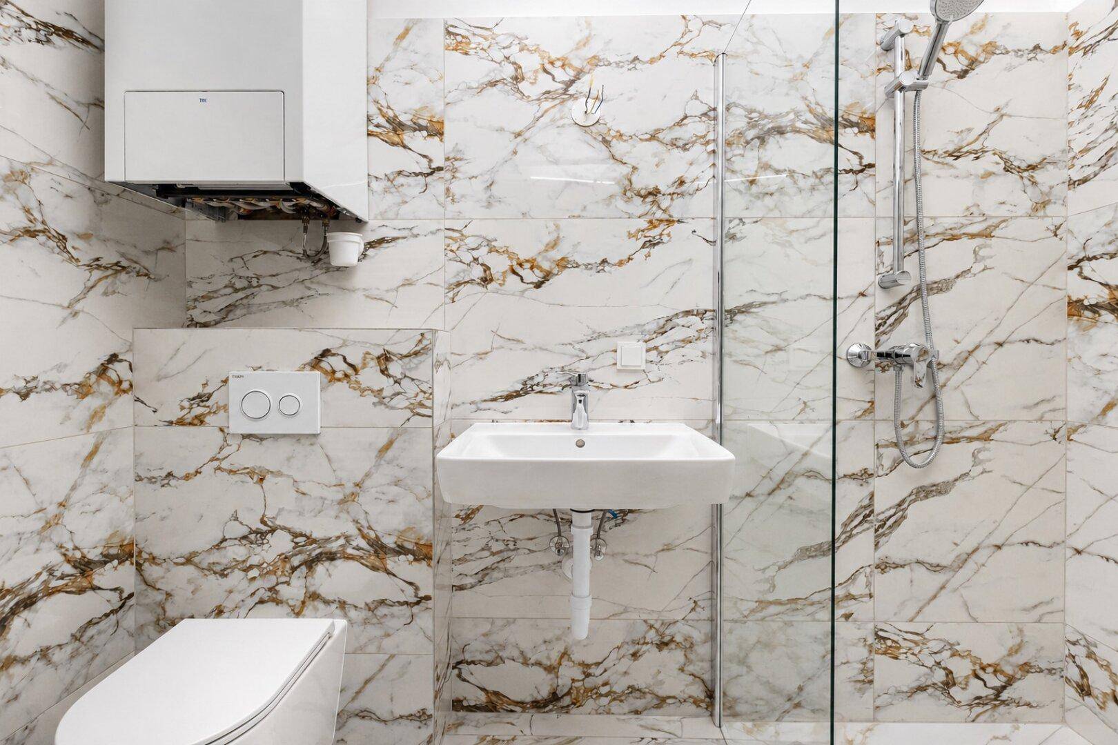 Modernes Badezimmer mit eleganten Marmorfliesen, Dusche und Waschbecken in zeitgemäßem Design.
