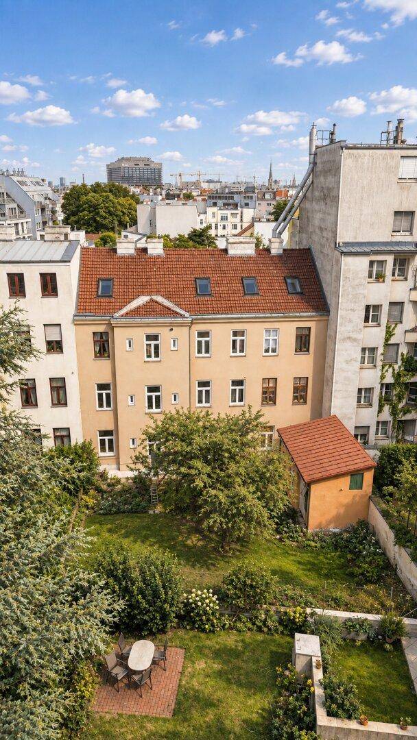 Luftaufnahme eines Wohnhauses mit gepflegtem Garten, Terrasse und Blick auf die Stadt.