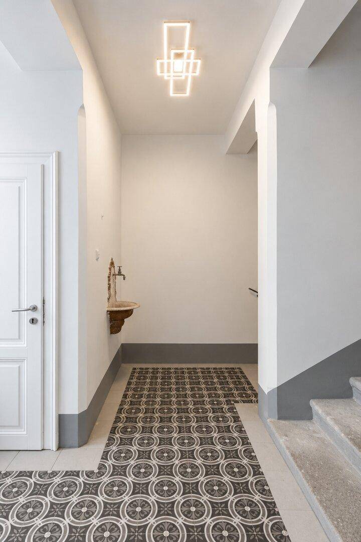 Heller Flur mit gemusterten Fliesen, modernem Licht und Zugang zum Treppenhaus.