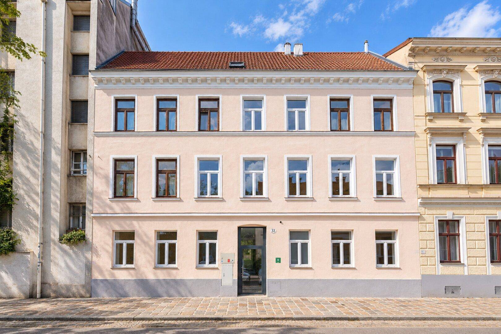 Klassische Fassade eines Mehrfamilienhauses mit vielen Fenstern und hellem Anstrich.