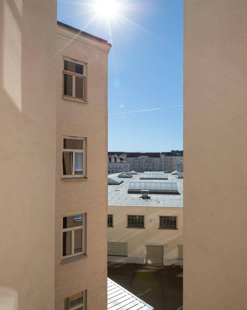 Blick zwischen Gebäuden auf Dächer und den blauen Himmel mit Sonnenschein.
