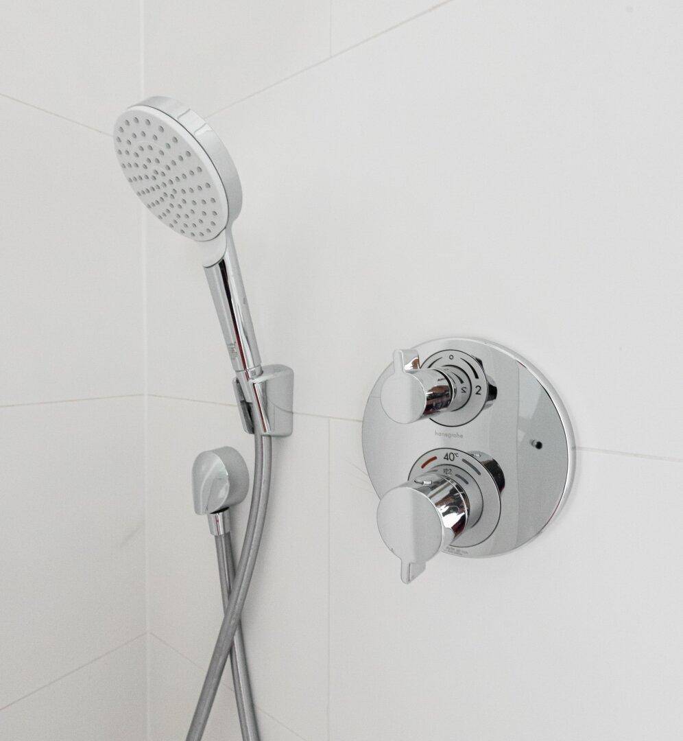 Detailaufnahme einer modernen Duscharmatur mit Handbrause und Temperaturregler.