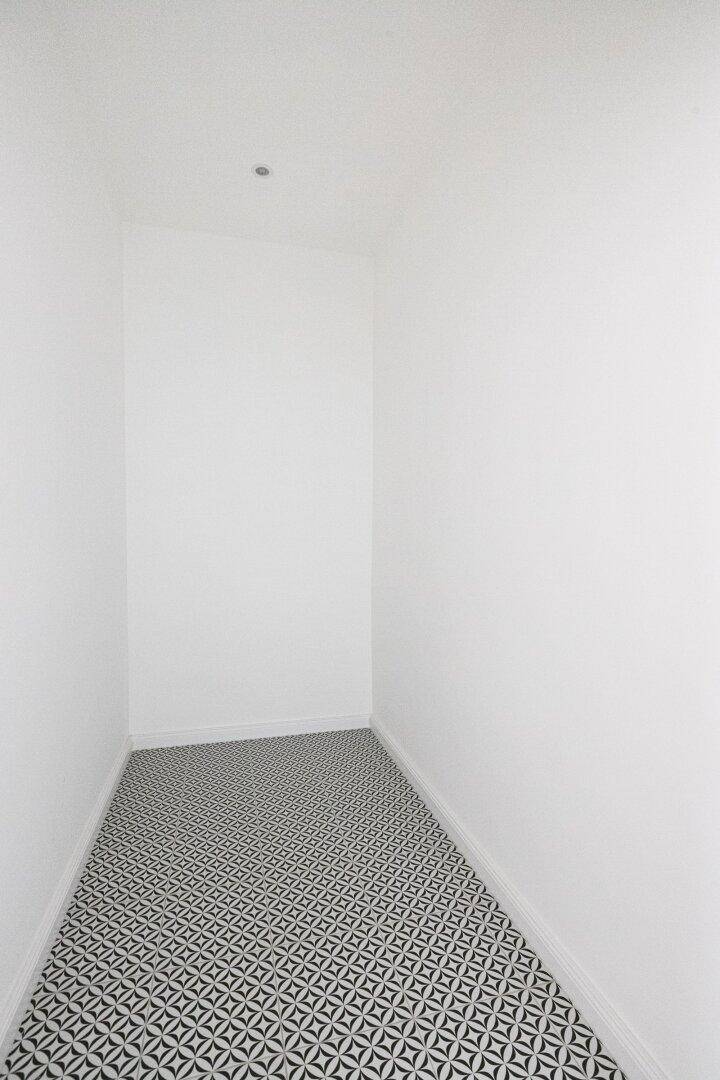 Schmaler, leerer Raum mit gemustertem Fliesenboden, ideal als Abstellraum.