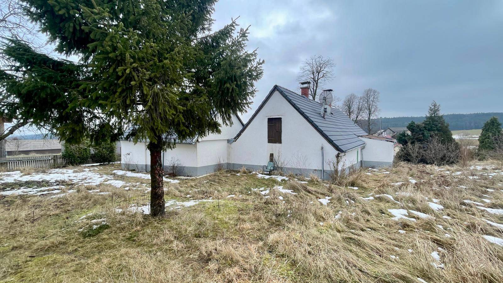 Freistehendes Haus in ländlicher Umgebung mit Bäumen und trockenem Gras.
