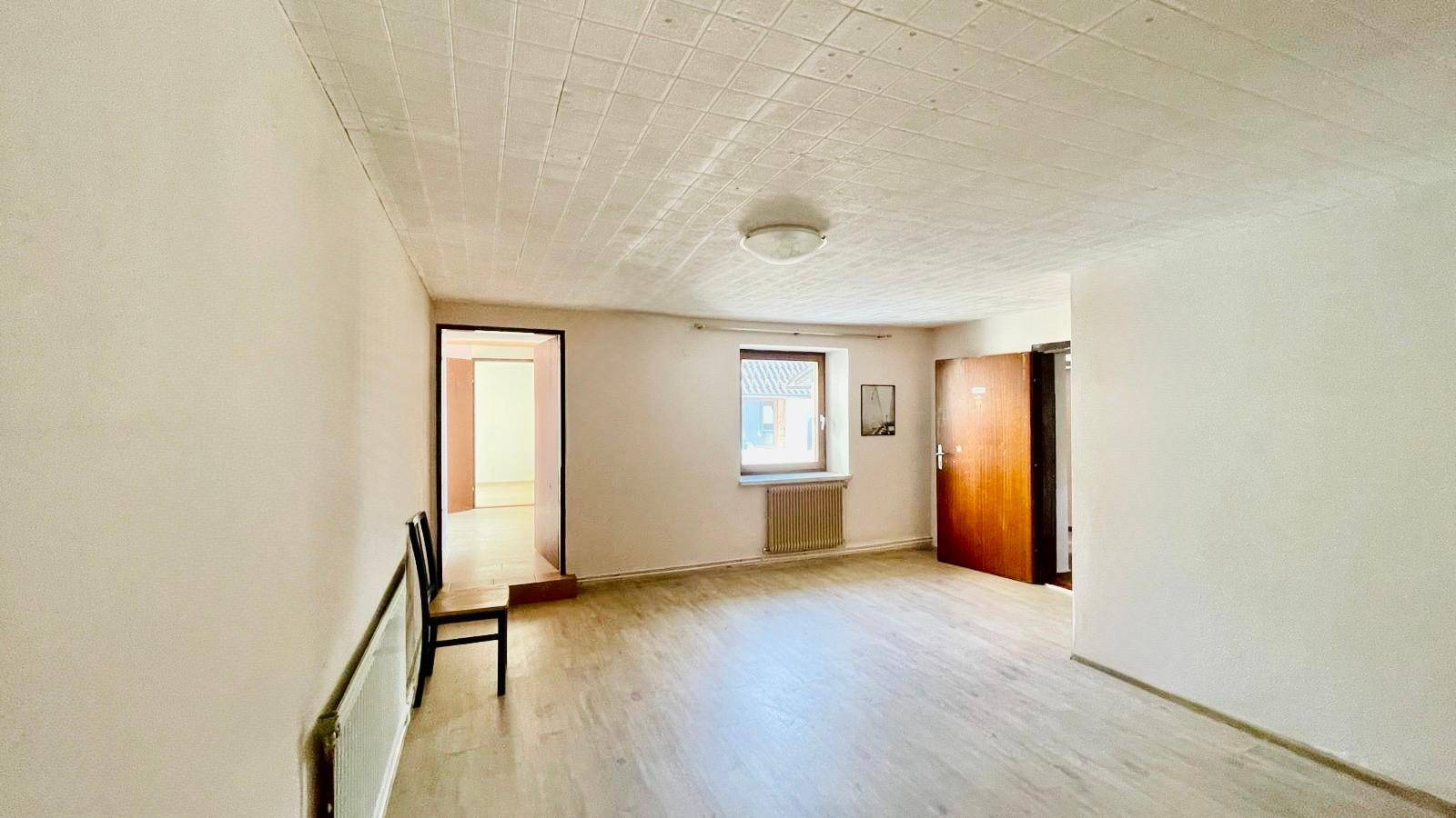 Flur mit hellem Laminatboden und Fenster, das Tageslicht hereinlässt.