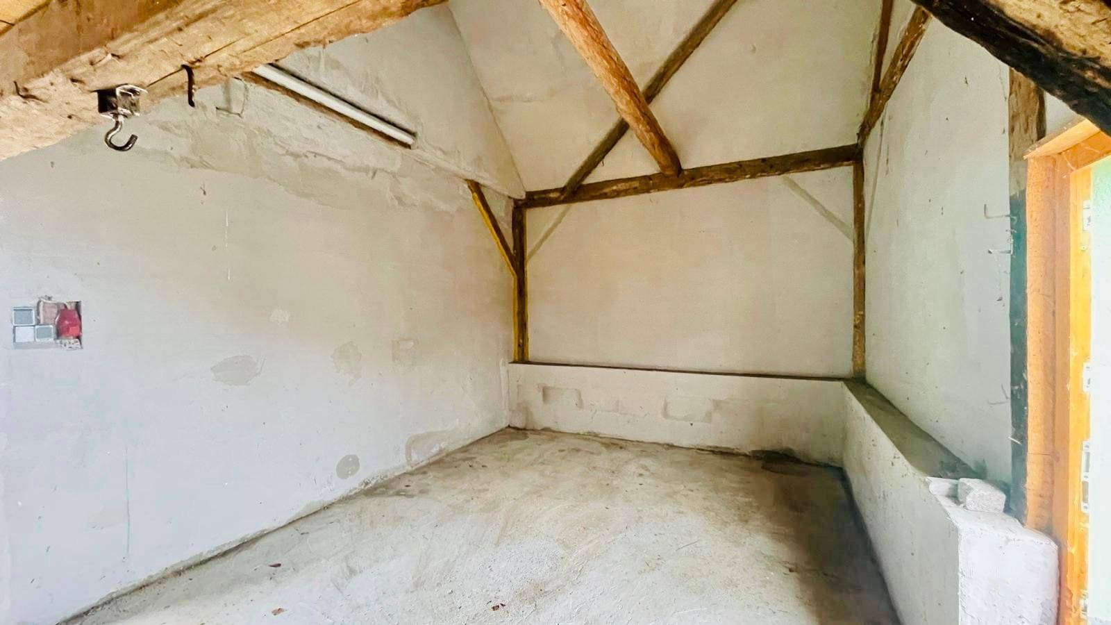 Unausgebauter Dachboden mit sichtbaren Holzbalken und schrägen Wänden.