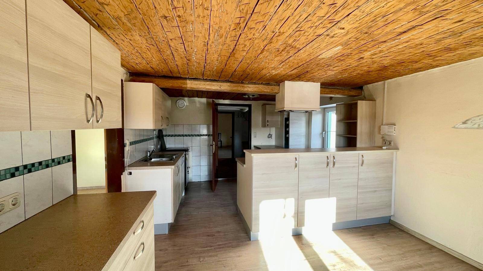 Geräumige Küche mit Holzdecken, hellen Schränken und viel Tageslicht.