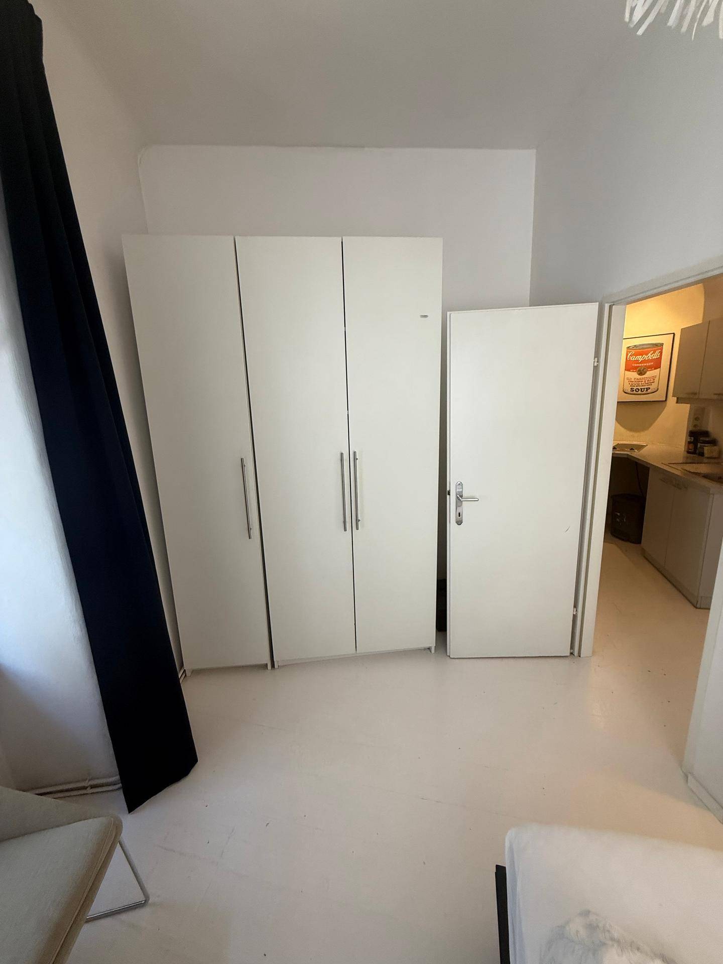 Schlafzimmer mit weißen Kleiderschränken und Zugang zu einem weiteren Raum.