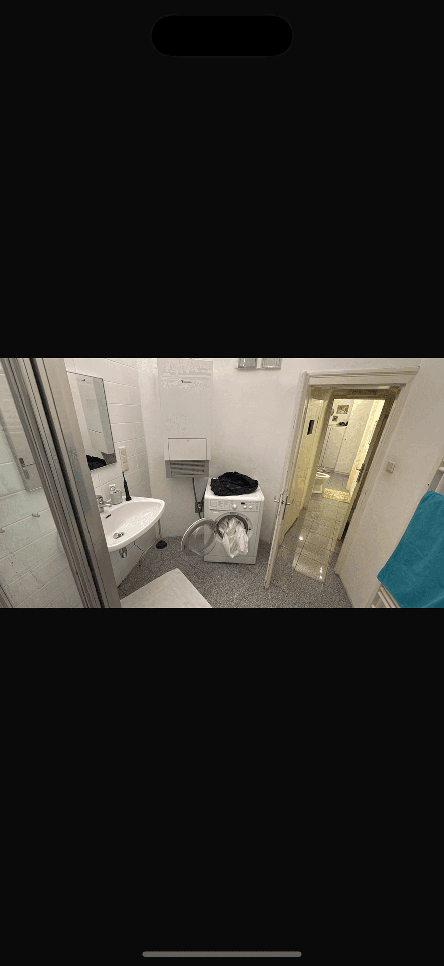 Funktionales Badezimmer mit Duschkabine, Waschbecken und einer Waschmaschine.