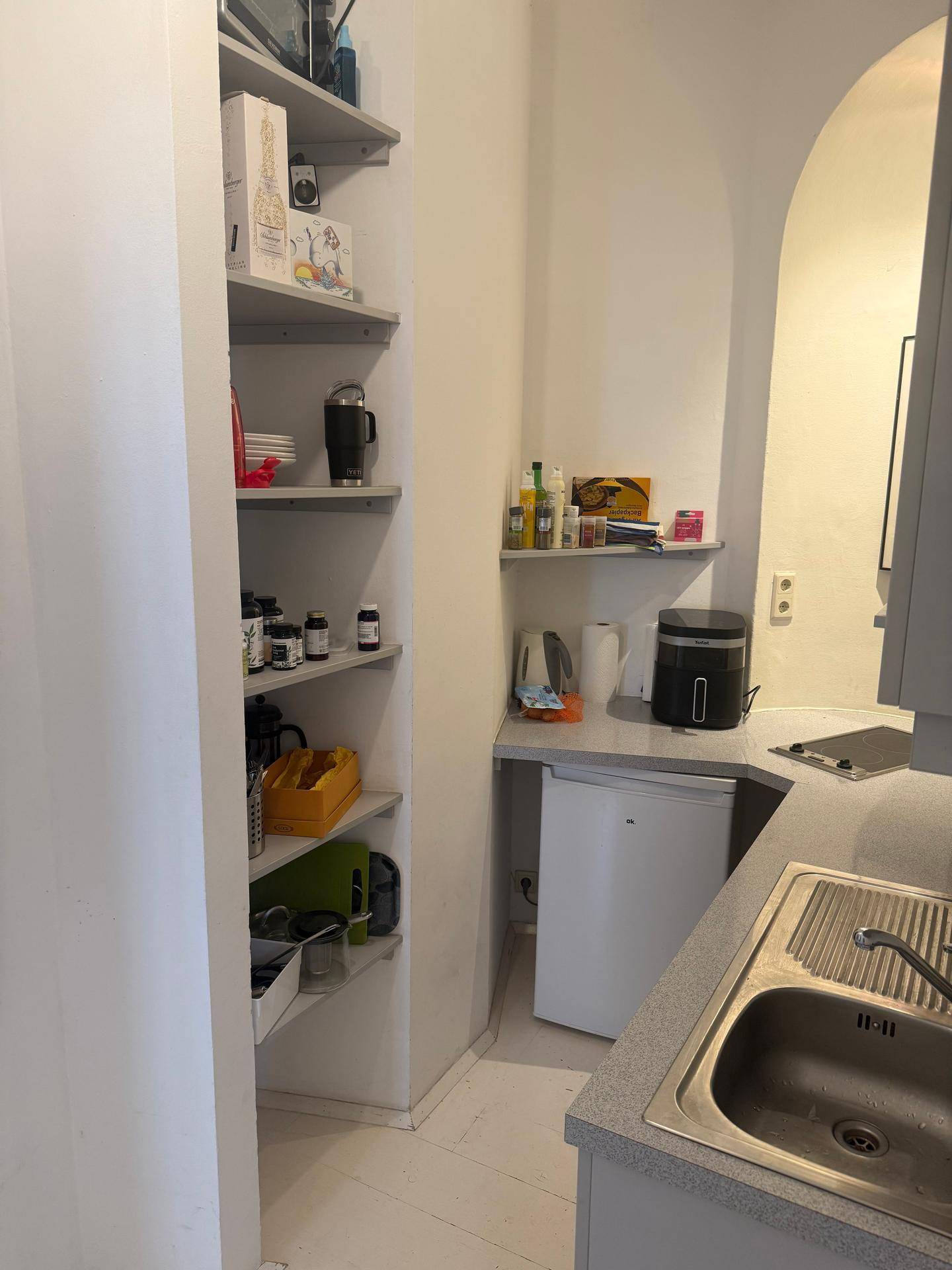 Funktionale Küchenzeile mit offenen Regalen und integrierten Geräten in einer hellen Nische.