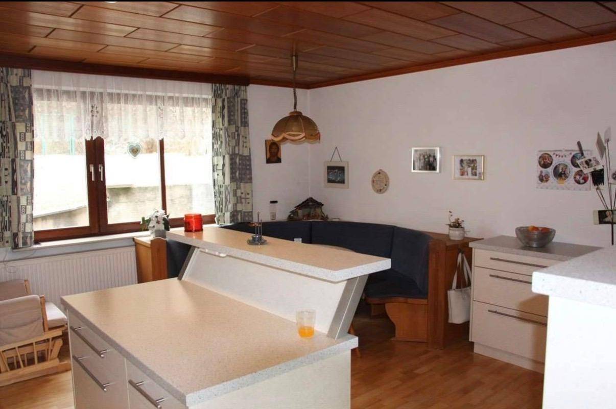 Gemütliche Wohnküche mit Frühstücksbar, Eckbank und Blick nach draußen durch das Fenster.