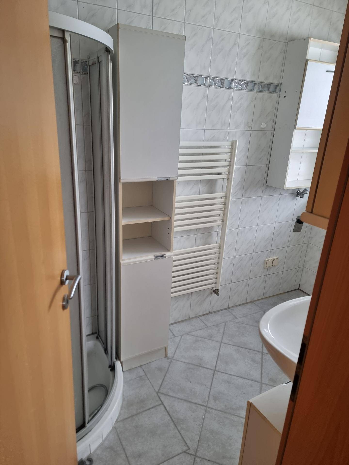 Badezimmer mit Eckdusche, hellen Fliesen und praktischem Handtuchheizkörper.