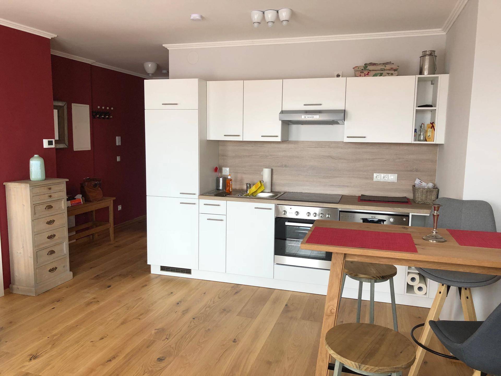 Funktionale Küchenzeile mit weißen Schränken, Holzarbeitsplatte und Essbereich.