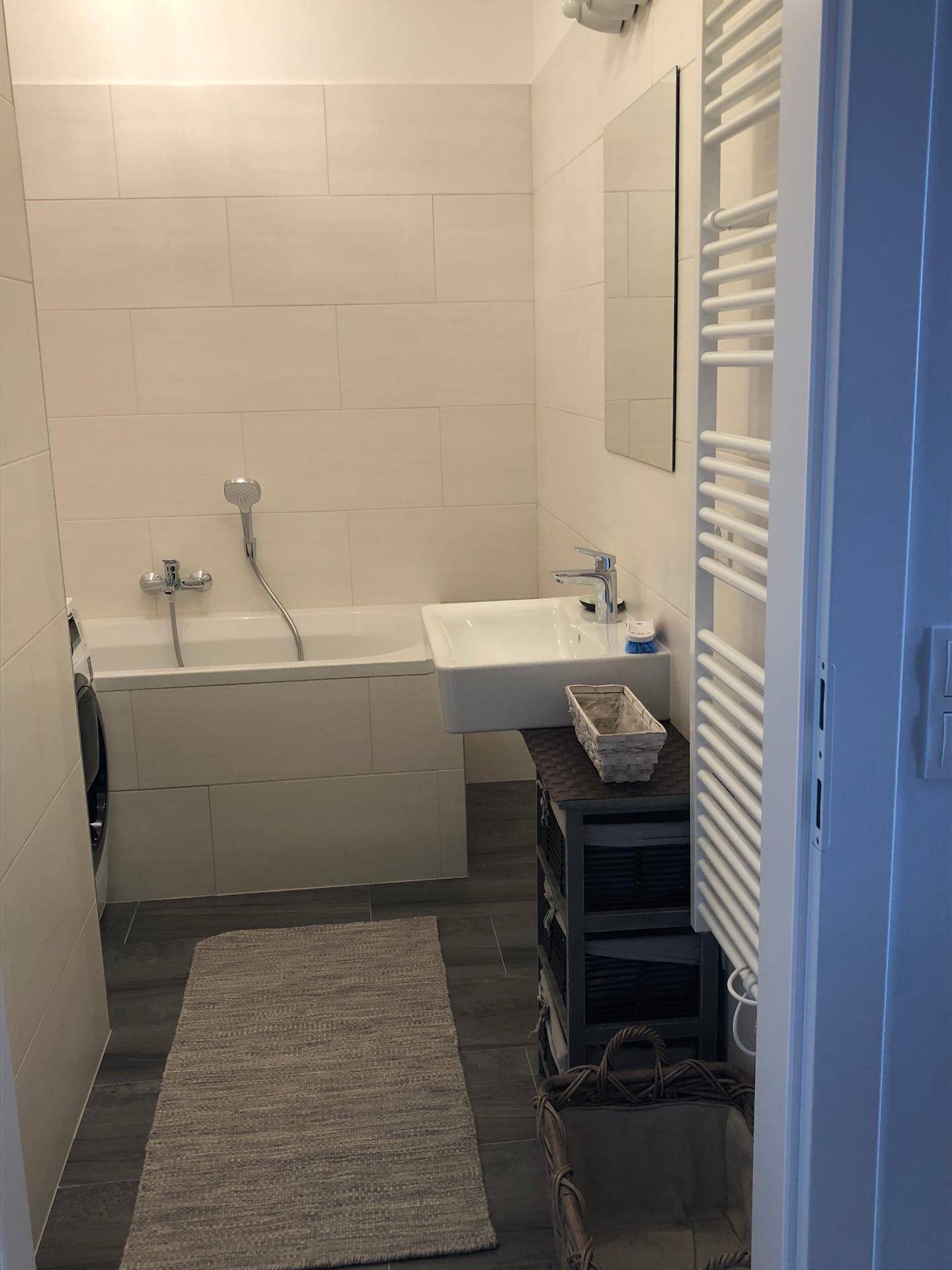 Modernes Badezimmer mit Badewanne, Waschbecken und beheiztem Handtuchhalter.