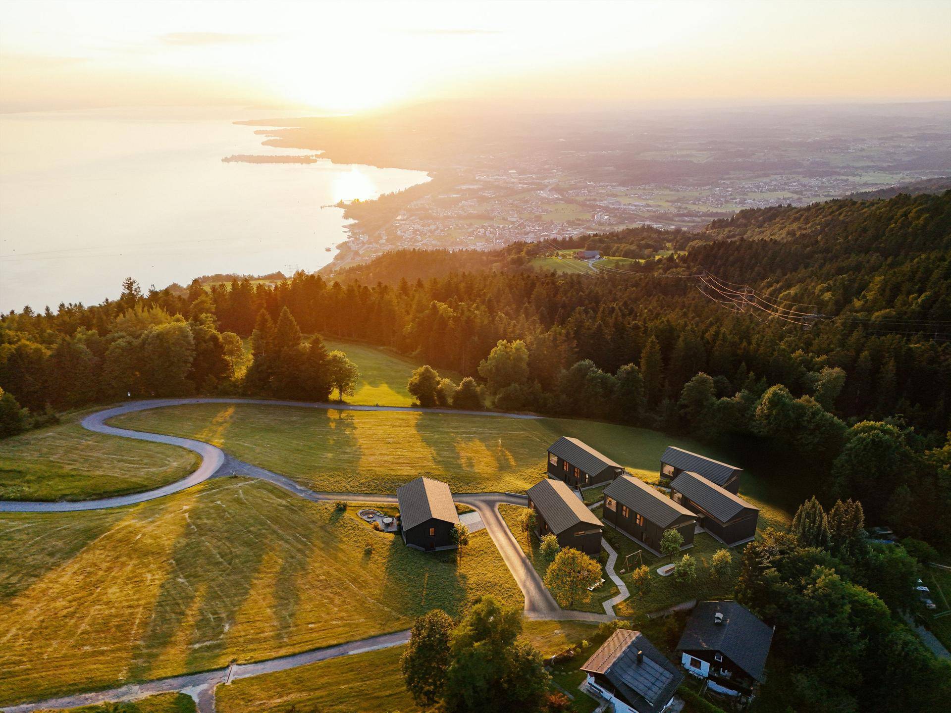 Spektakuläre Luftaufnahme der Häuser und des Sees bei Sonnenuntergang mit goldenem Licht.