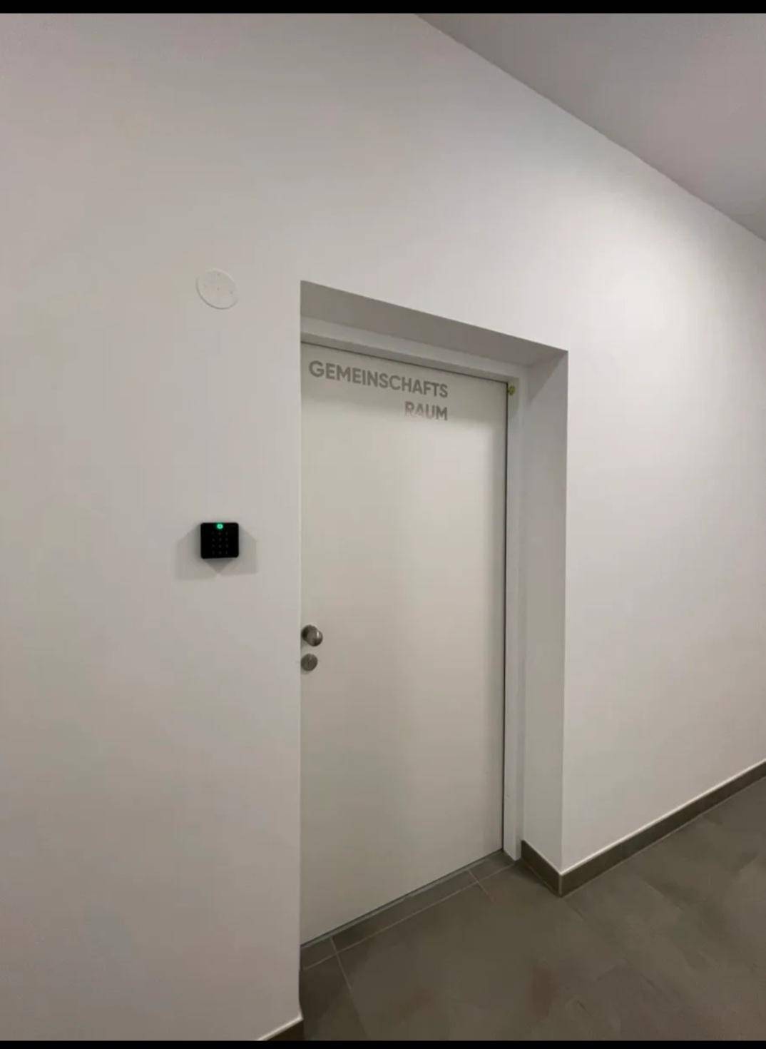 Tür zu einem Gemeinschaftsraum in einem Gebäude, zugänglich für Bewohner.