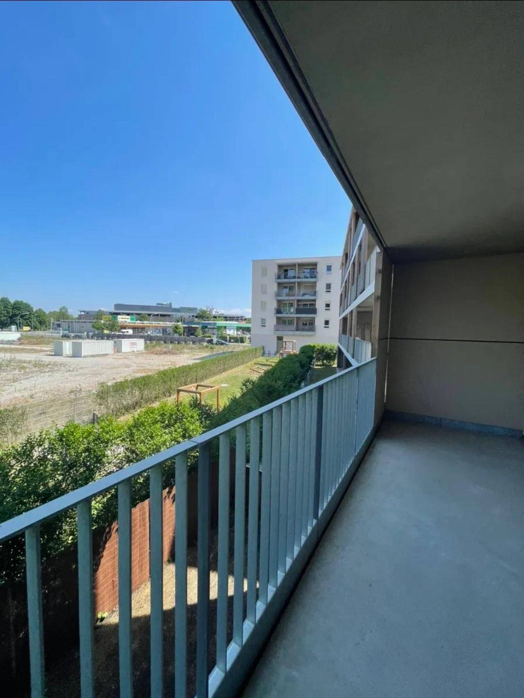 Langer Balkon mit Metallgeländer und Ausblick auf die Nachbarschaft und Grünflächen.