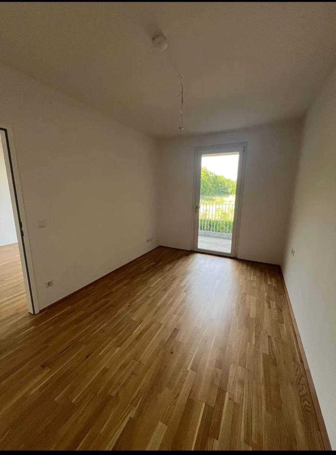 Helles Schlafzimmer mit Holzboden und direktem Zugang zu einem Balkon.